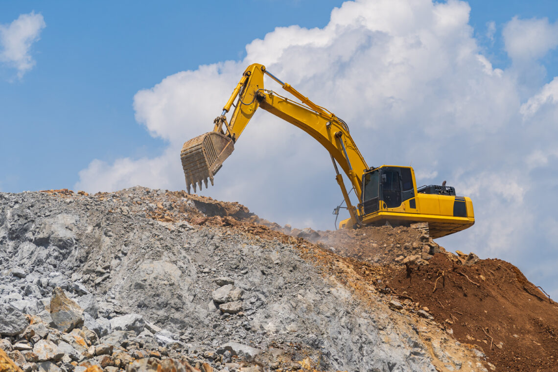 Ein gelber Bagger arbeitet auf felsigem Untergrund unter blauem Himmel – Symbol für das gemeinsame Arbeiten an einer Beziehung in der Krise.